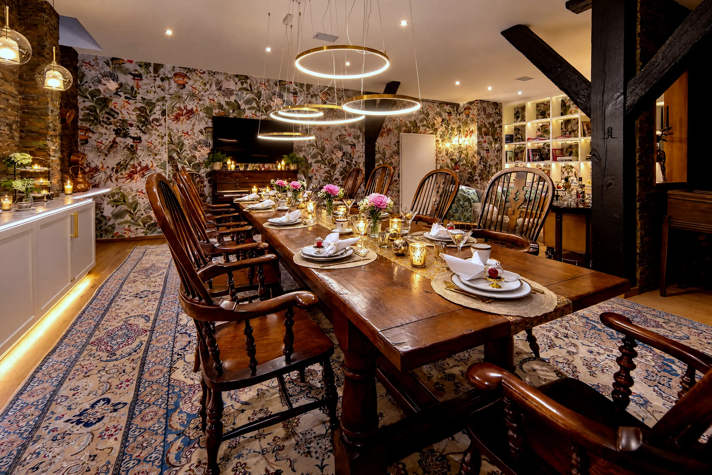 Die lange Tafel am Abend, gedeckt, dahinter Bibliothek und Kaminlounge, links der Flügel